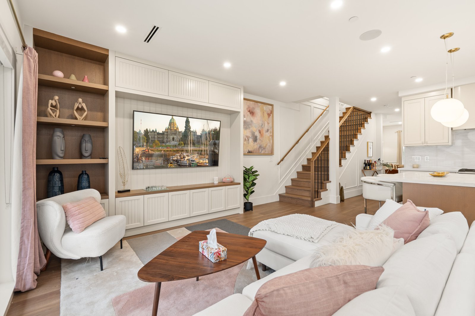 Bright living room with white sectional sofa, built-in shelving and staircase