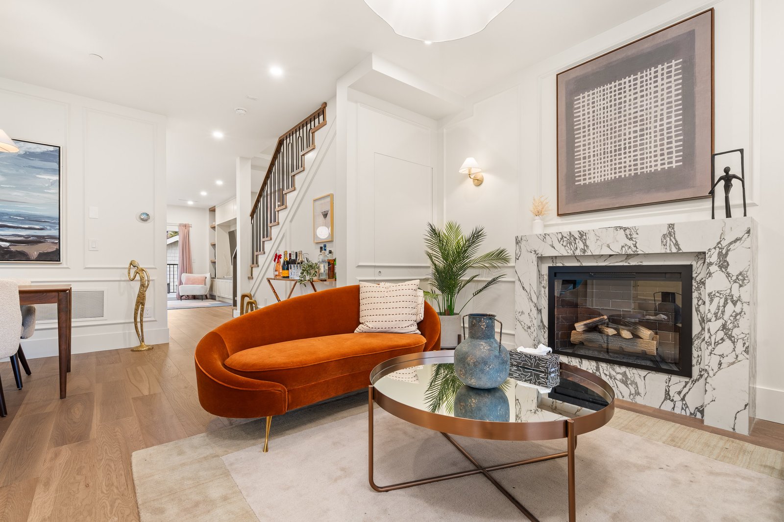 Living room with orange sofa, round coffee table and marble fireplace