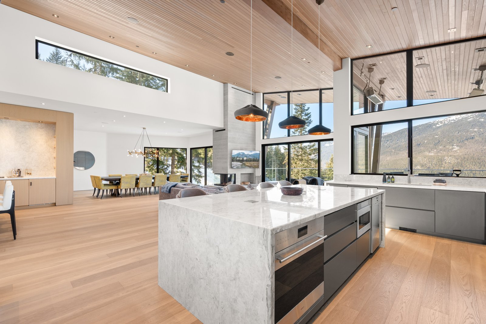 Modern open-plan kitchen and living room with marble island and wood ceiling